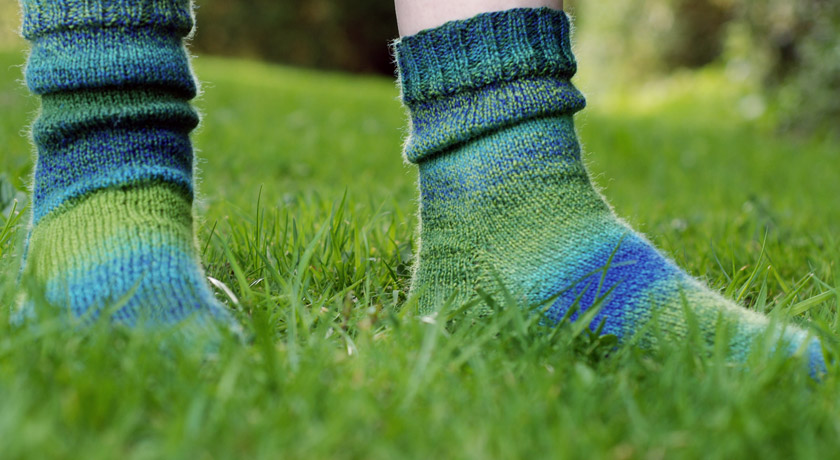 Side view of green and blue knitted socks on grass