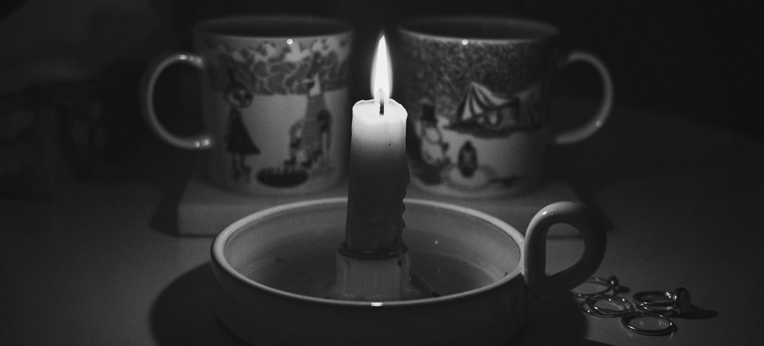 Candle in front of mugs