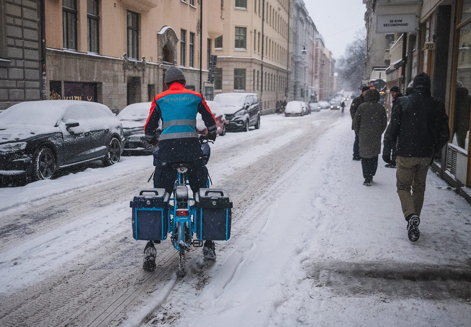 Postman cycling through snow
