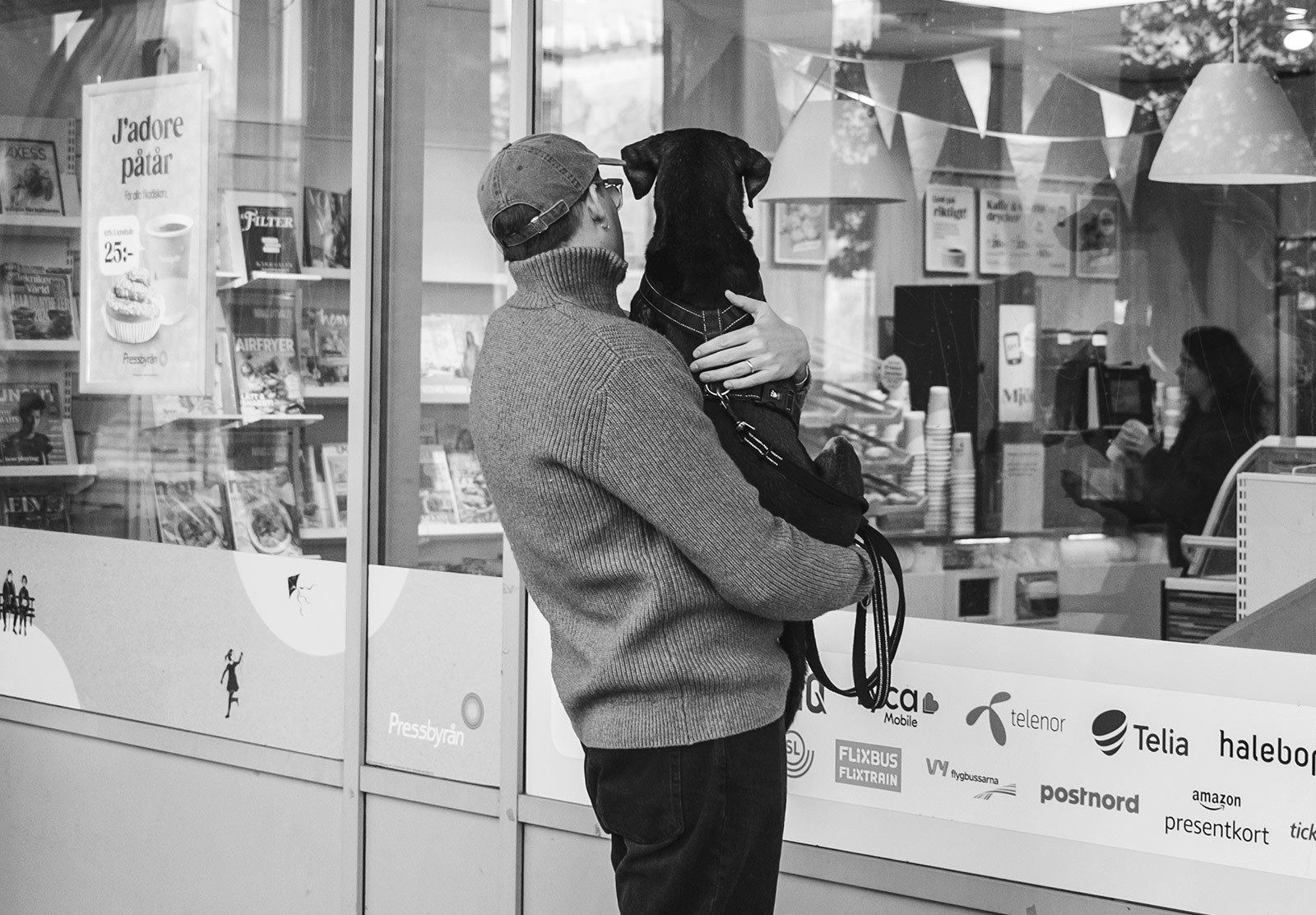 Man hold a dog and waiting outside a shop