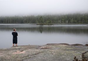 Man standing at foggy lake