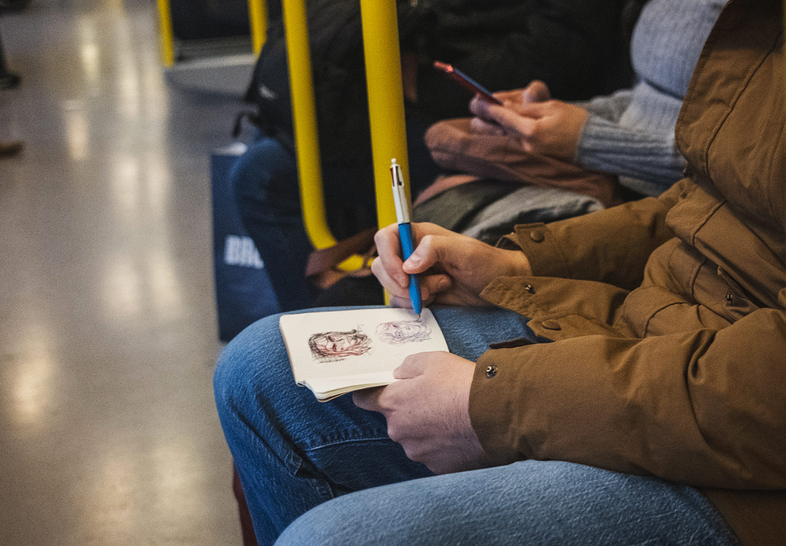 Man sketching faces on train
