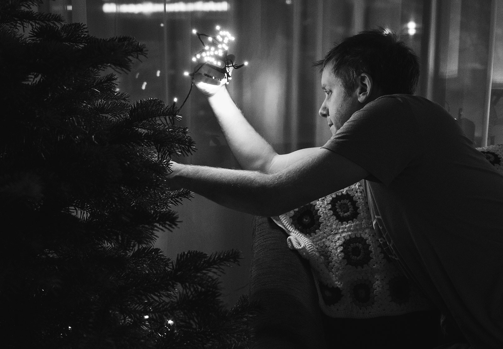 Man putting lights on Christmas tree